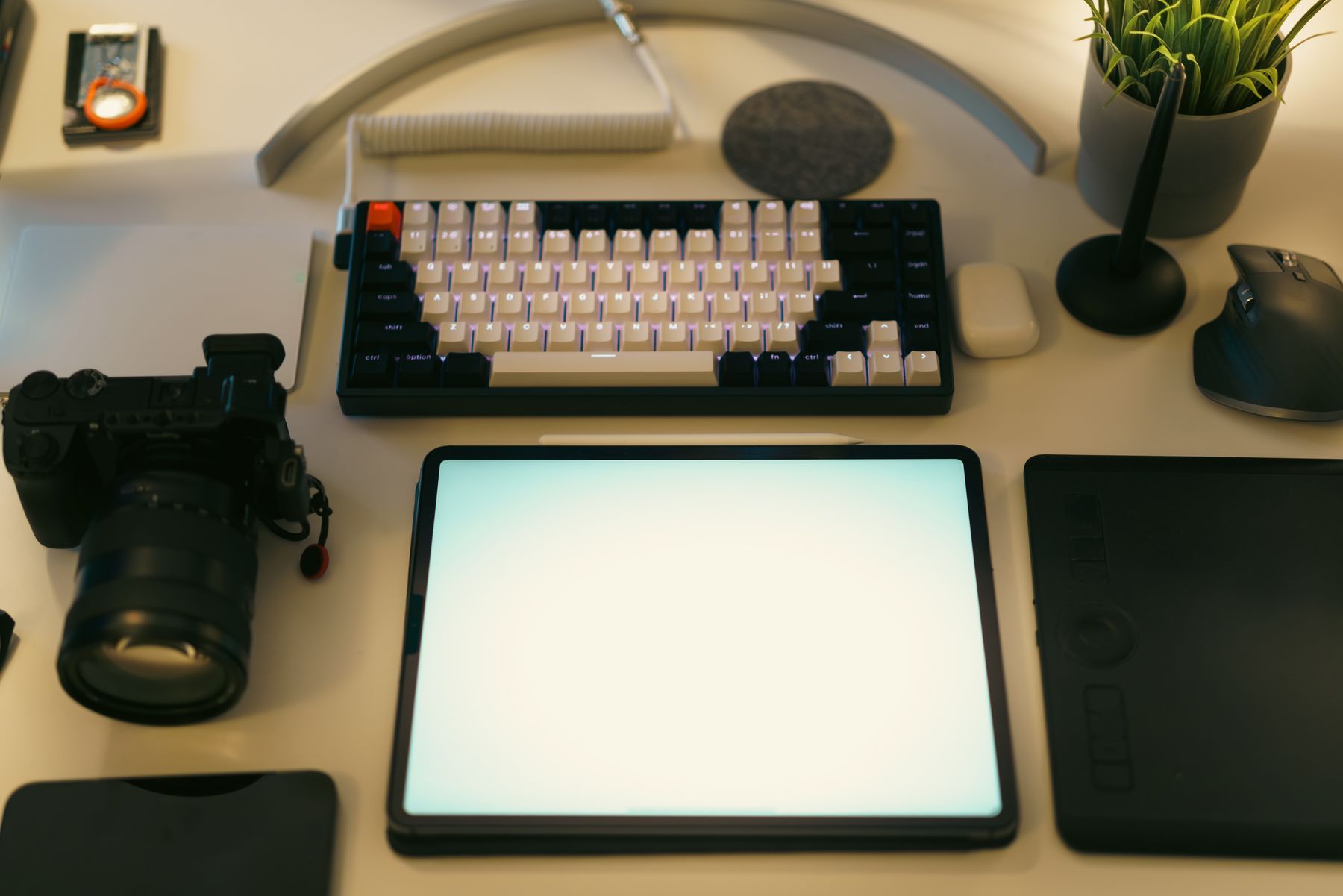 Mesa de trabalho criativa com câmera, tablet e teclado